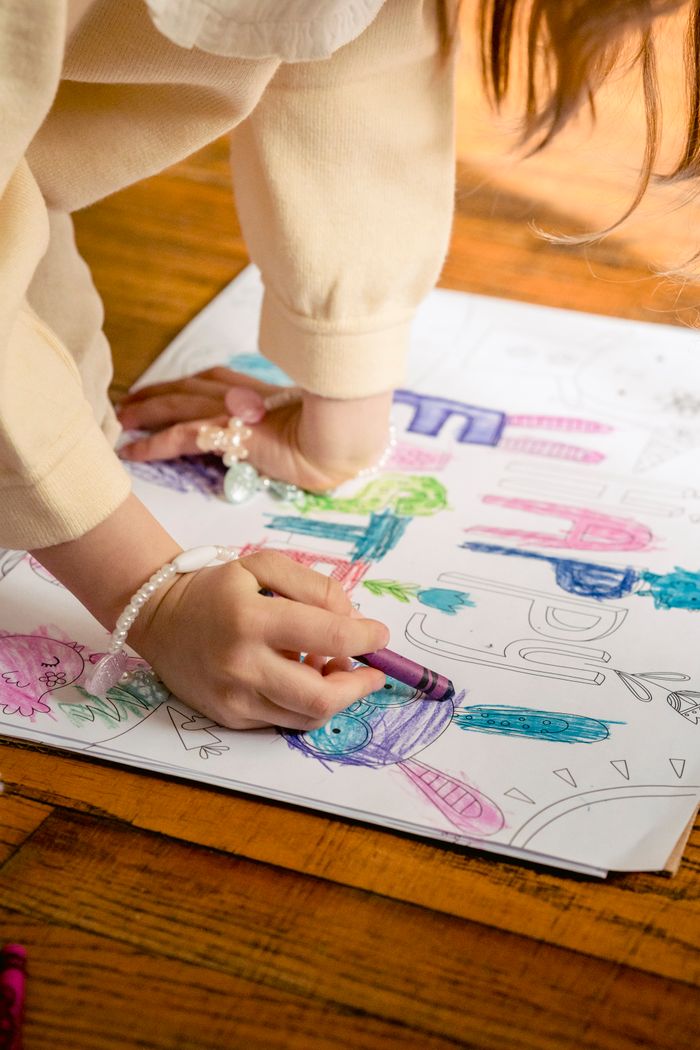 services-01 Crop anonymous girl in casual clothes drawing in coloring book at home in daytime